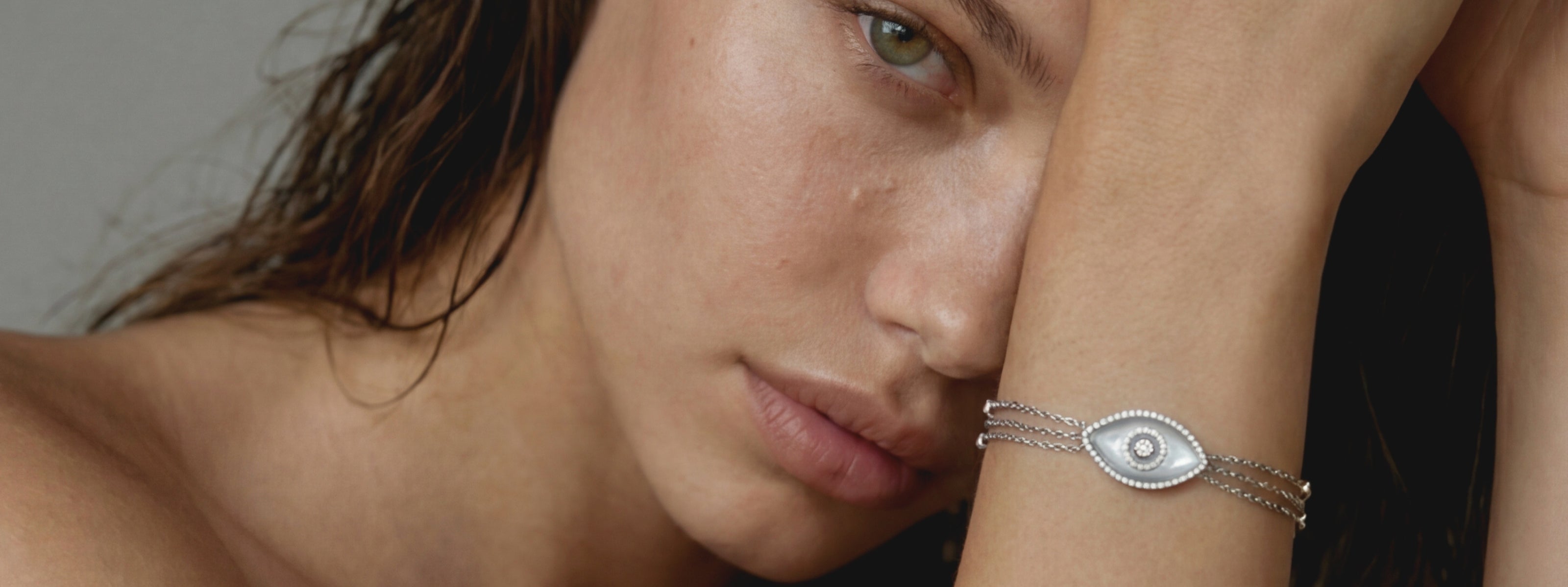 Woman wearing a bracelet in 14K white gold with an evil eye in mother of pearl and pavé white diamonds