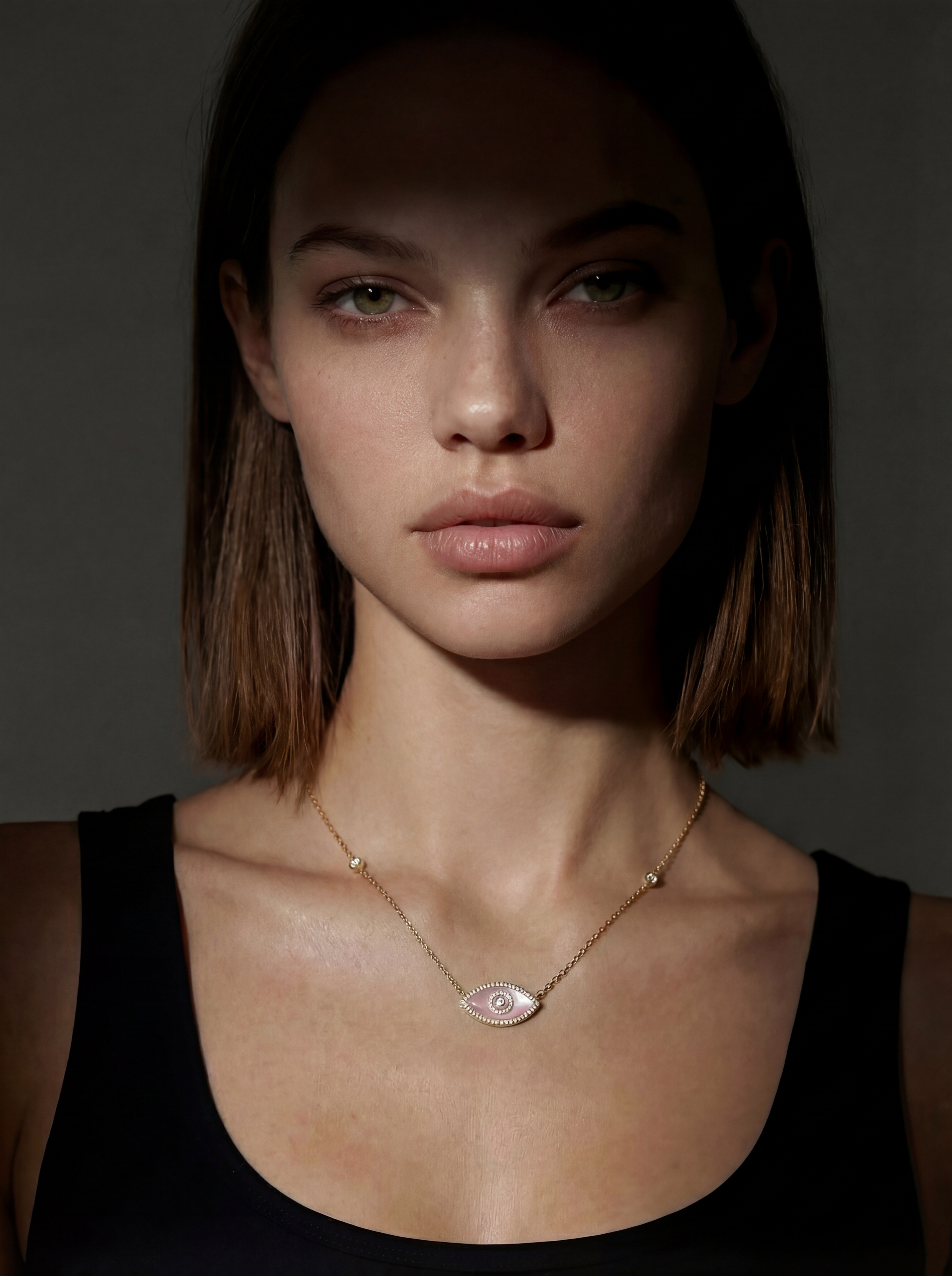 Woman wearing a necklace in 14K gold with an evil eye in pink opal and pavé white diamonds